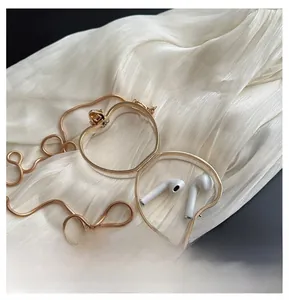 Detail of golden apple-shaped metal clutch open showing interior capacity with earbuds