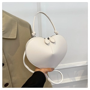 Detail shot of the white heart-shaped crossbody bag with smooth finish and dual zippers
