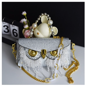 Detailed view of silver rhinestone owl evening bag with fringe tassels and pearl handle