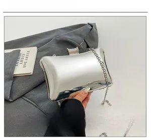 Silberne Spiegel-Clutch mit Strassverschluss und Kette, präsentiert auf grauem Anzug