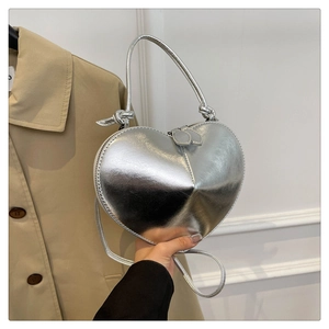 Detail of silver heart-shaped bag showing metallic texture and knotted handle design