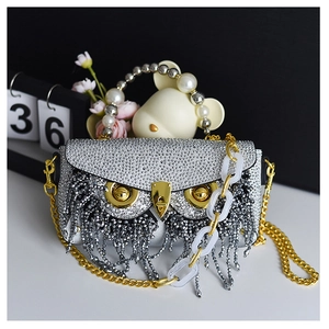 Detailed view of silver rhinestone owl clutch with pearl handle and long bead fringe