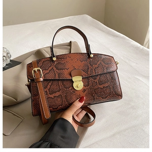 Close-up of brown snake skin textured tote bag with golden metal twist lock closure