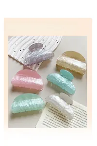 Detail of six marble pattern acrylic hair claws in assorted pastel colors on a tray