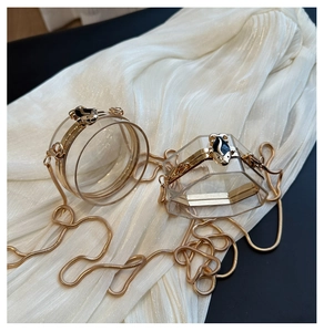 Detailed macro view of clear acrylic evening bags with fish-shaped gold metal clasps