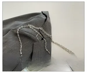 Detail eines polierten silbernen Metallkettenriemens auf grauem Stoff für die Box Bag
