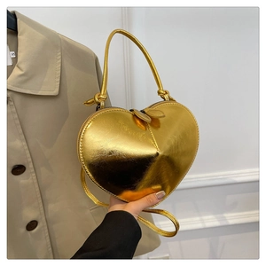 Close-up of golden heart-shaped handbag with glossy finish and dual zipper detail