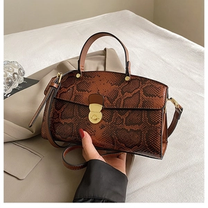 Detail of dark brown python-textured faux leather tote bag with golden semicircular clasp