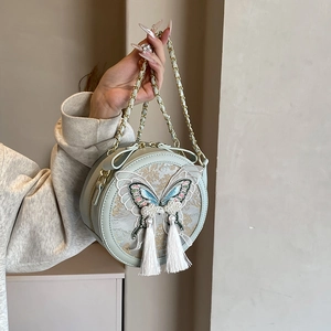Petit sac rond vert menthe style chinois avec broderie papillon et pompons blancs