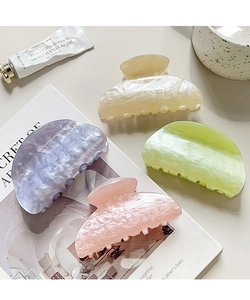 Detail of four acetate hair claws with marble texture in pastel colors on a magazine