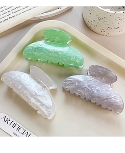 Three marble texture acrylic hair claws in green, white and purple in a tray