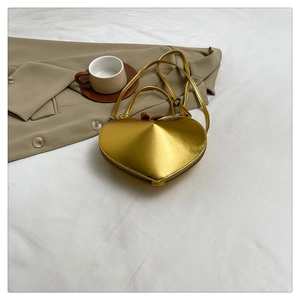 Detailed top view of a metallic gold heart-shaped bag on a cozy white fabric background