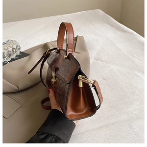 Close-up of brown lizard texture on a small faux leather handbag with gold metal clasp