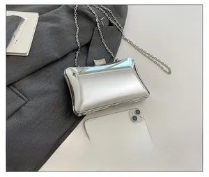 Detail einer silbernen Spiegel-Clutch mit Strassverschluss und Metallkettenriemen