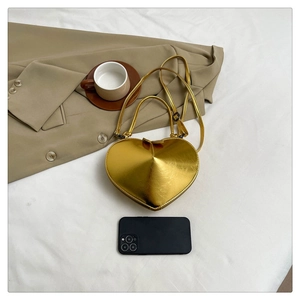 Detailed view of the gold heart-shaped crossbody bag with a mobile phone for size reference