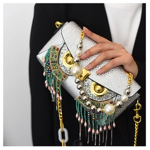 Close-up of owl-shaped rhinestone evening clutch with beaded tassels and gold metal accents