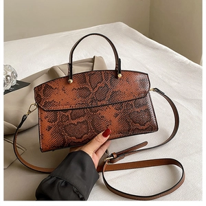 Detailed close-up of brown snakeskin texture and gold hardware on large tote bag
