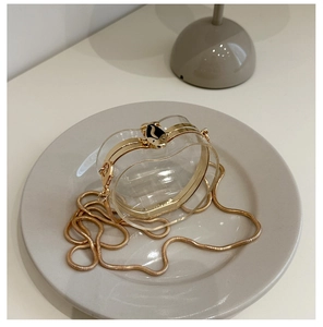 Detailed shot of apple-shaped acrylic bag with gold metal frame and bear-shaped clasp