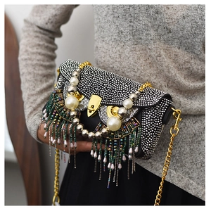 Detail of owl clutch bag with sparkling rhinestones, pearl eyes and colorful long tassels