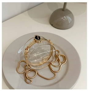 Detail of round acrylic clutch bag with golden chain and unique cat head clasp closure