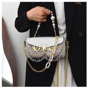 Detail of owl clutch bag with silver rhinestones, pearl handle, and beaded tassels