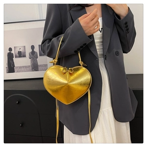 Detailed close-up of a glossy gold heart-shaped handbag with premium metallic texture