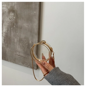 Close-up of a round transparent acrylic jelly bag with gold metal frame and chain strap