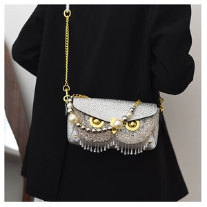 Detail of silver owl bag with sparkling rhinestones, pearls and crystal tassels on chain