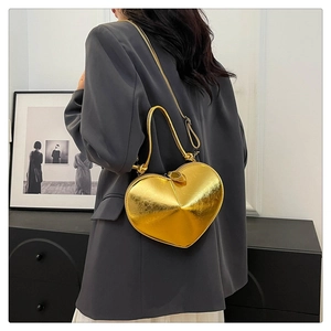 Close-up of golden metallic heart-shaped handbag worn over a dark grey blazer