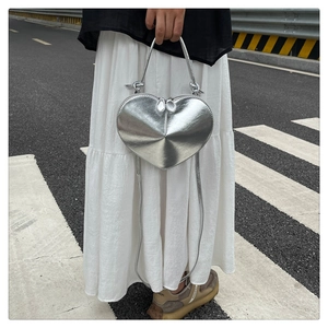 Detail of silver heart-shaped crossbody bag with metallic finish and dual zippers