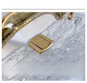 Detail of golden metal lock and water ripple texture on transparent acrylic handbag