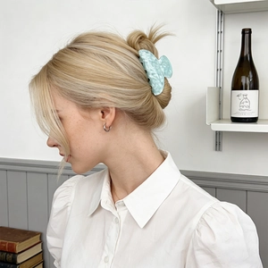 Elegant marble pattern light blue hair claw clip shown on model in a minimalist setting