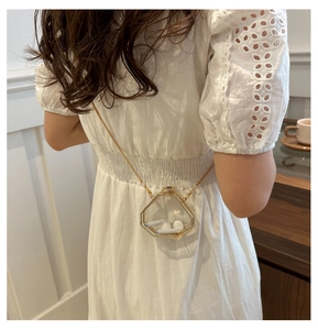 Detail of transparent geometric mini bag with gold chain strap and wireless earphones