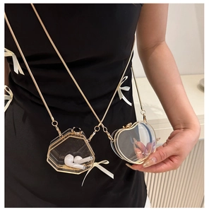 Detail of transparent acrylic mini heart bag with gold metal frame and snake chain strap