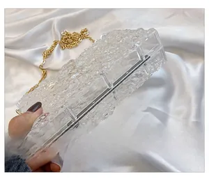 Detail view of acrylic clutch bag featuring ice crack texture and golden chain strap
