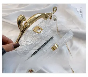 Detail of clear acrylic evening bag with ice-crack texture and golden leopard handle