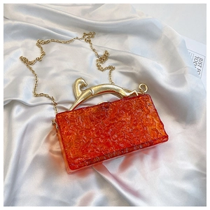 Detail of orange acrylic evening bag with gold leopard handle and ice-crack texture