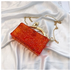 Macro view of orange ice-crack acrylic evening bag with golden leopard clasp and chain