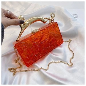 Detail of orange acrylic bag featuring a gold leopard handle and water ripple texture
