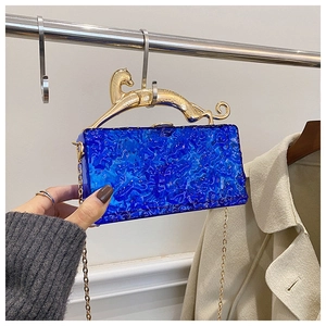 Detail of blue acrylic clutch featuring a water ripple texture and gold leopard handle