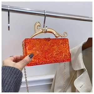 Detail of orange acrylic clutch with golden cheetah handle and ice crack texture
