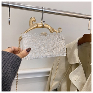 Detail of clear acrylic evening clutch with gold cheetah handle and ice-crack pattern
