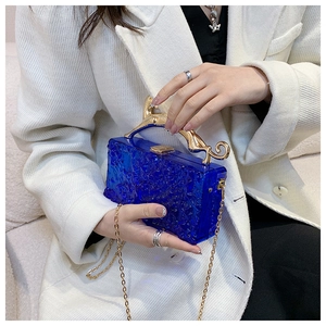 Detailed view of blue acrylic evening bag with ice-crack texture and golden leopard handle