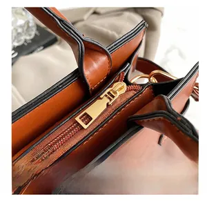 Detailed close-up of premium smooth golden zipper and black oil edge on brown leather bag