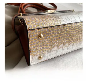 Detail of stone textured tote bag base with protective gold metal studs and white faux leather