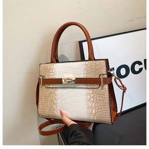 Detail of crocodile pattern tote bag featuring contrast colors and metallic twist lock