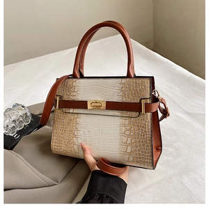 Detail of crocodile pattern leather tote with golden twist lock and gradient brown finish