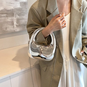 Borsa a mano argento specchiato dal design futuristico con catena e modella in verde