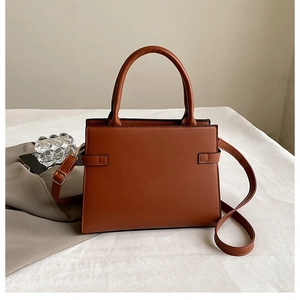 Detailed close-up of caramel brown tote bag with structured handle and leather texture