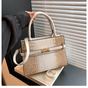 Close-up of white and gold crocodile pattern tote bag with metal twist lock and handle